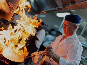 chef cooking over a stove in a restaurant kitchen